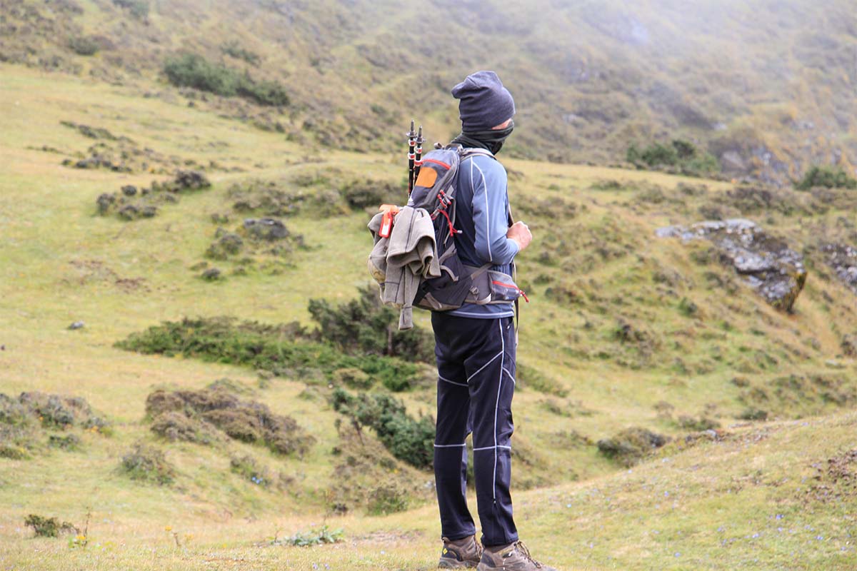 A trekker with a backpack and trekking poles looking out over the alpine mountains of Annapurna.